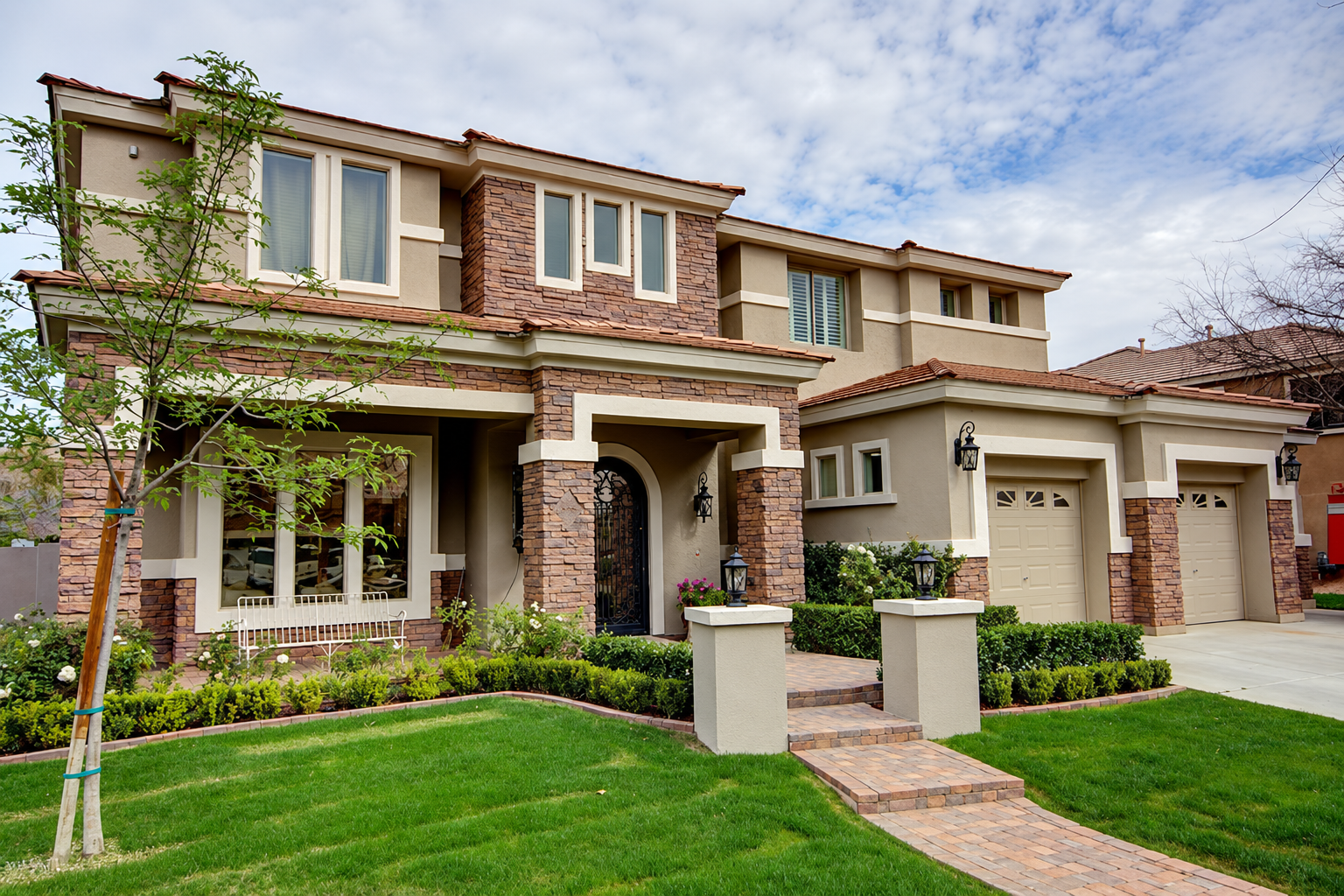 Two-story stucco home with stone accents and landscaped front yard